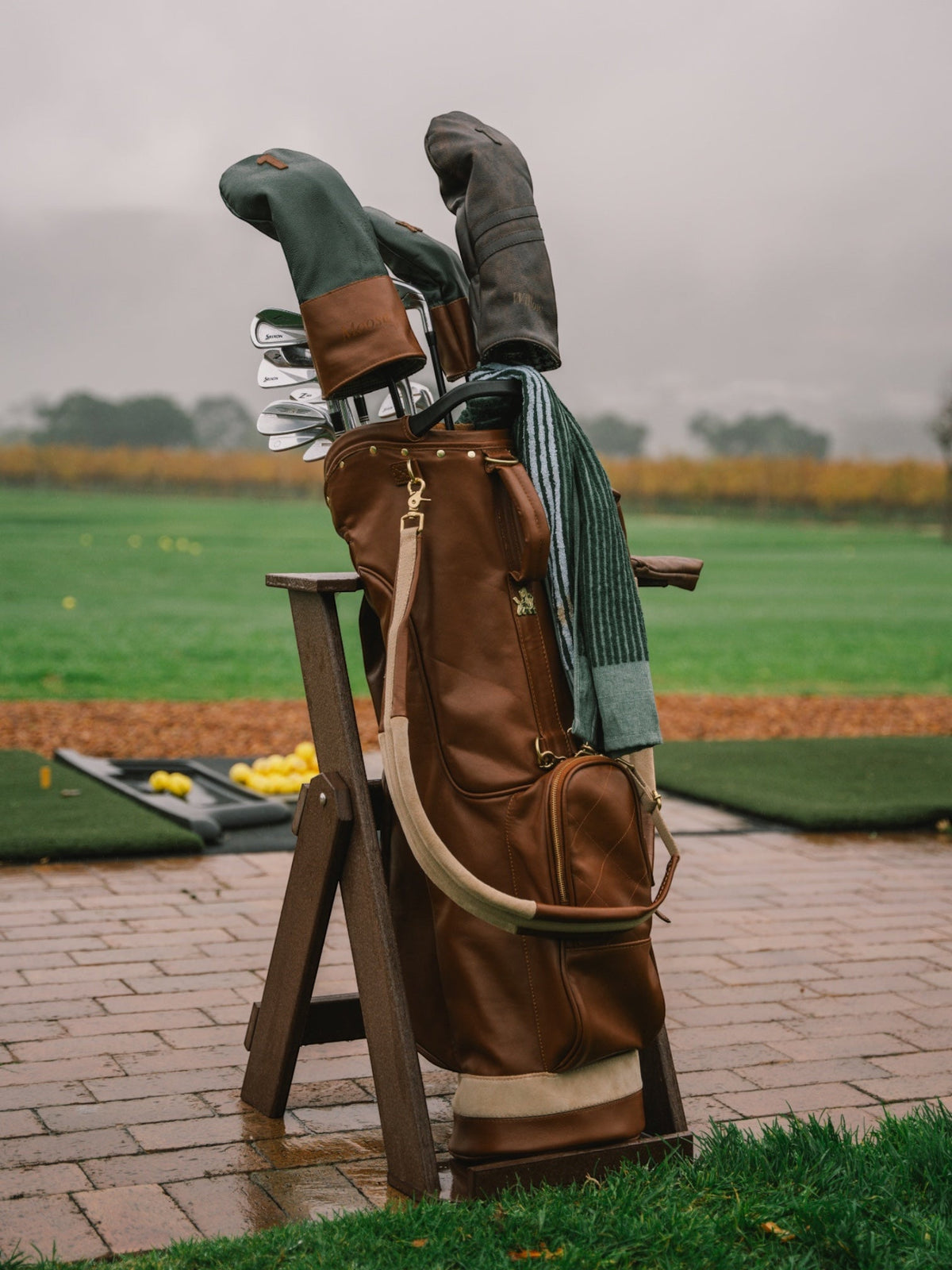 Black and tan leather golf bag with headcovers, on the rocks at golden hour