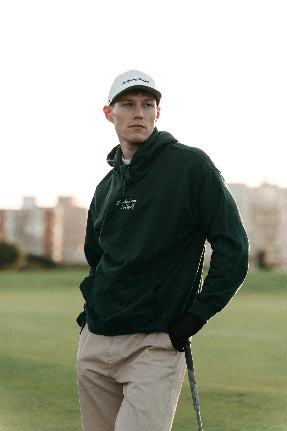 Golfer in a forest green Lovely Day For Golf hoodie on the fairway