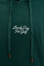 Cream script Lovely Day For Golf chest embroidery on the forest green hoodie