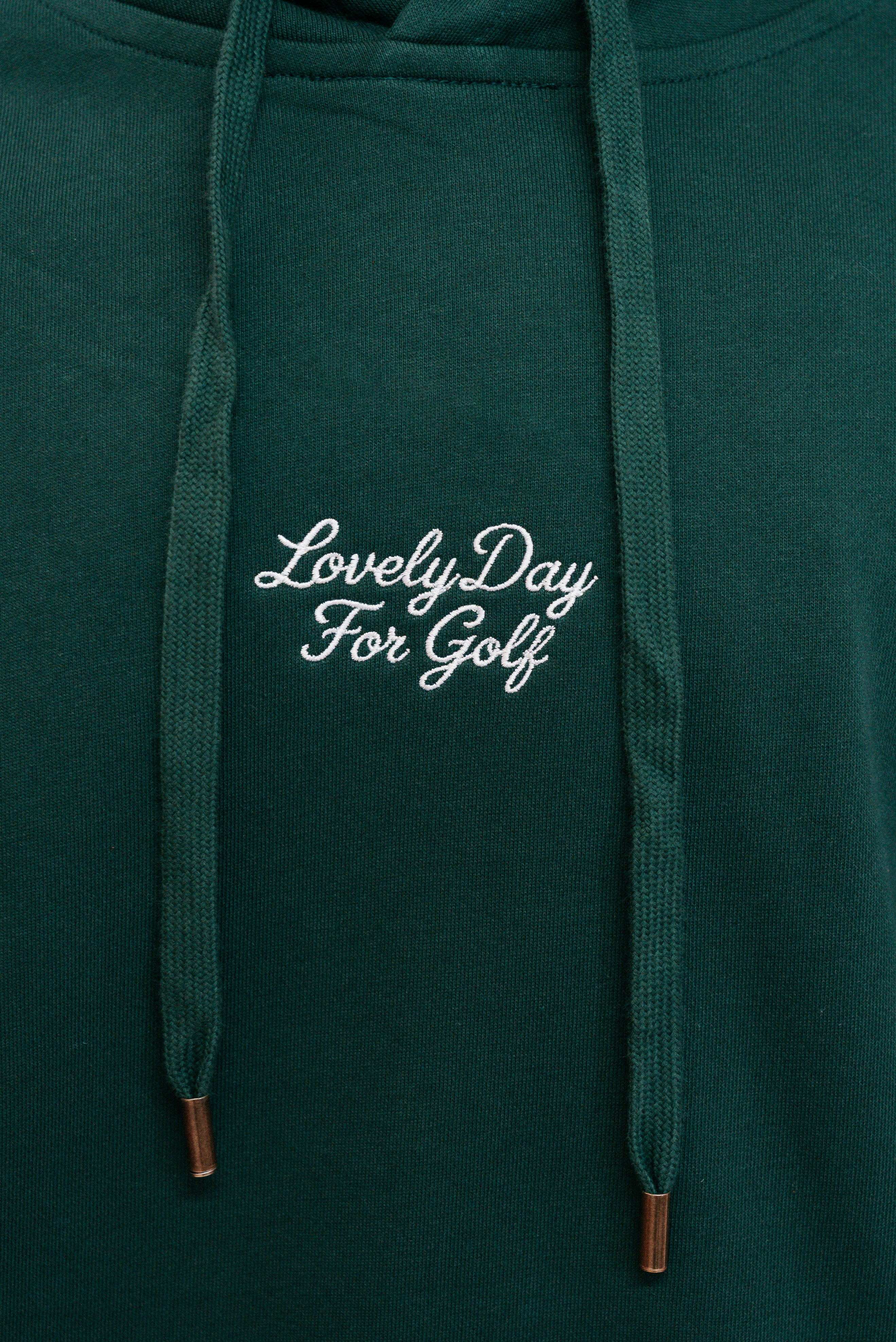Cream script Lovely Day For Golf chest embroidery on the forest green hoodie