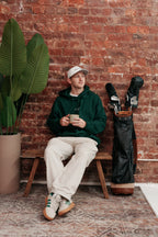 Forest green hoodie worn seated against a brick wall